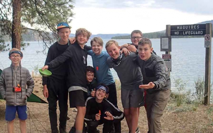 a group of boys smile at the camera beside a lake on an outward bound expedition in washington state
